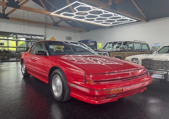 1990 Oldsmobile Trofeo — red coupe in modern garage showroom